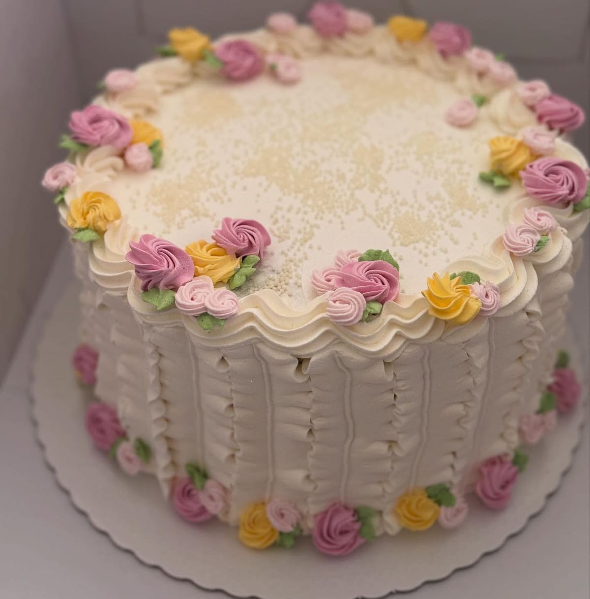 Bolo vintage branco com bordas de chantilly e florzinhas rosa, lilás e amarelas